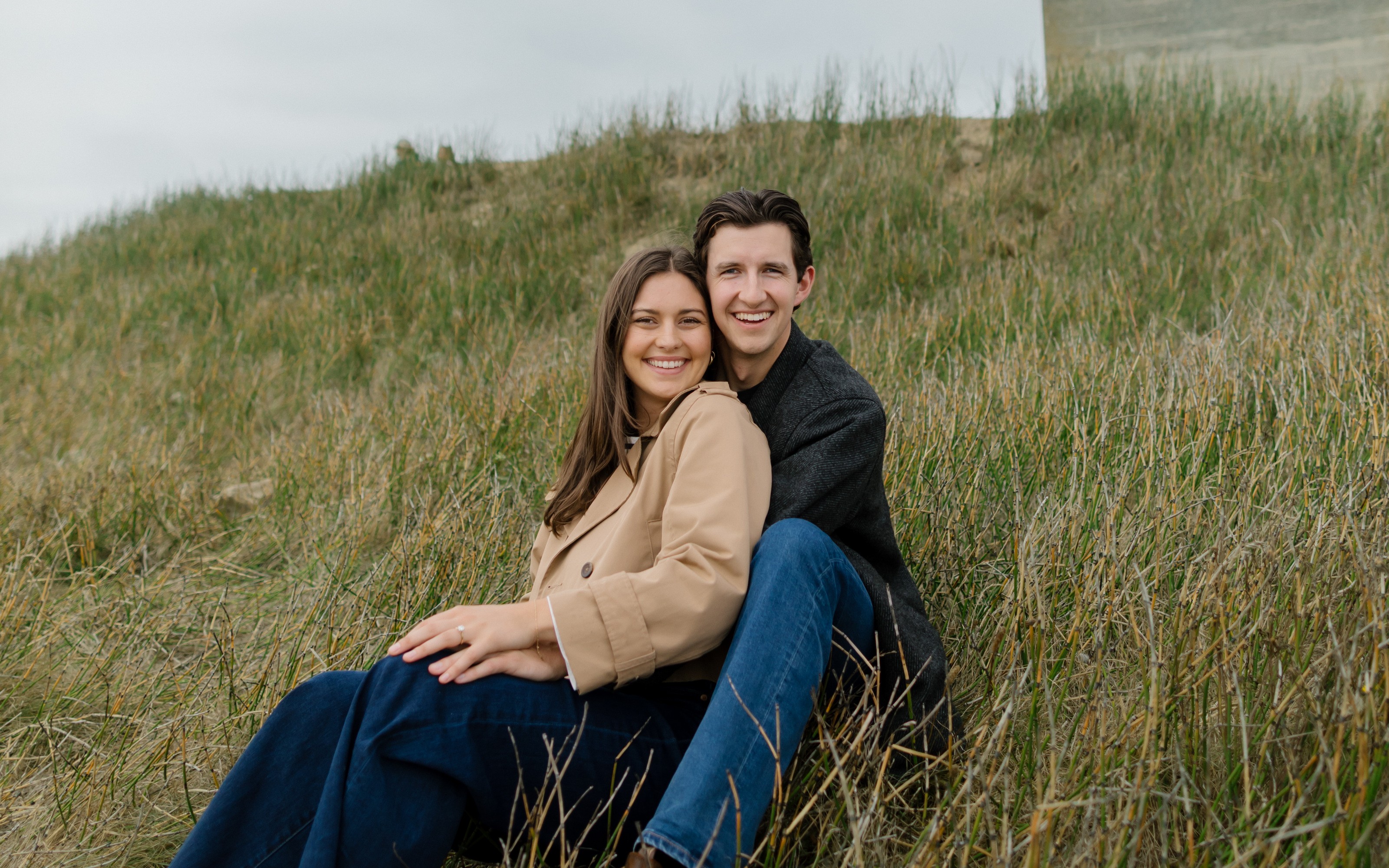 Ellie and Graham sitting in the grass below Cattle Point lighthouse